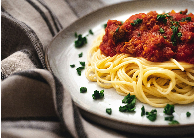 a plate of spaghetti centered off to the right side with a table cloth bunched up umderneath it