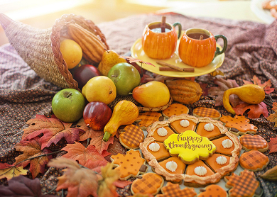 a thankgiving picnic with a cornucopia full of fruit and iced cookies in the shape of a pie